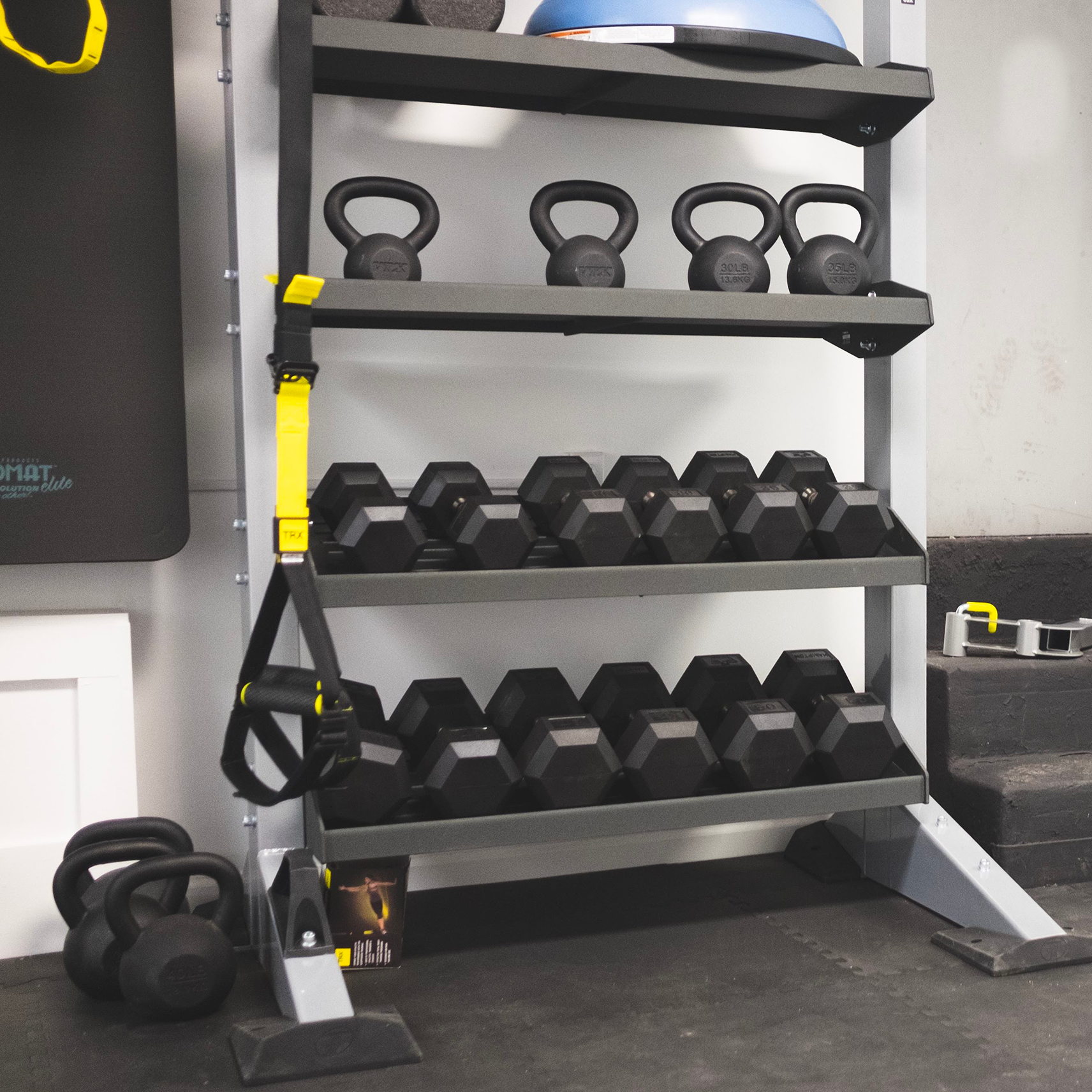 A women's fitness gym rack with kettlebells and weights on it.