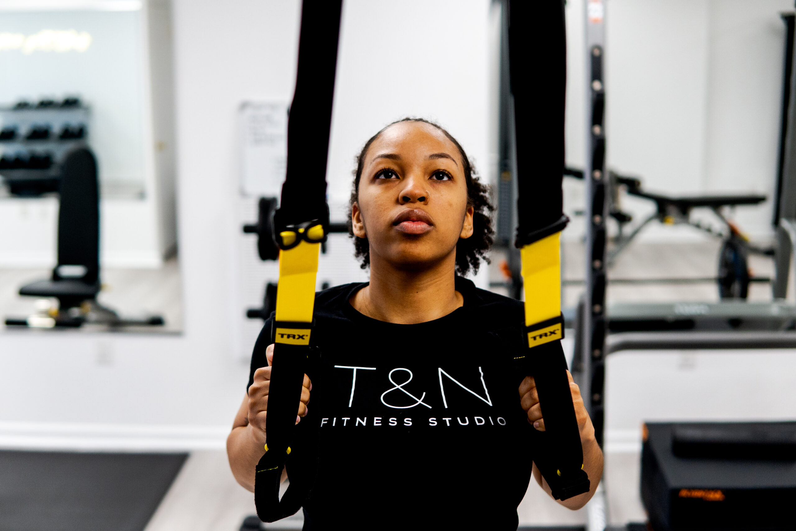 A woman intensifying her home workouts with a trx strap in a gym.