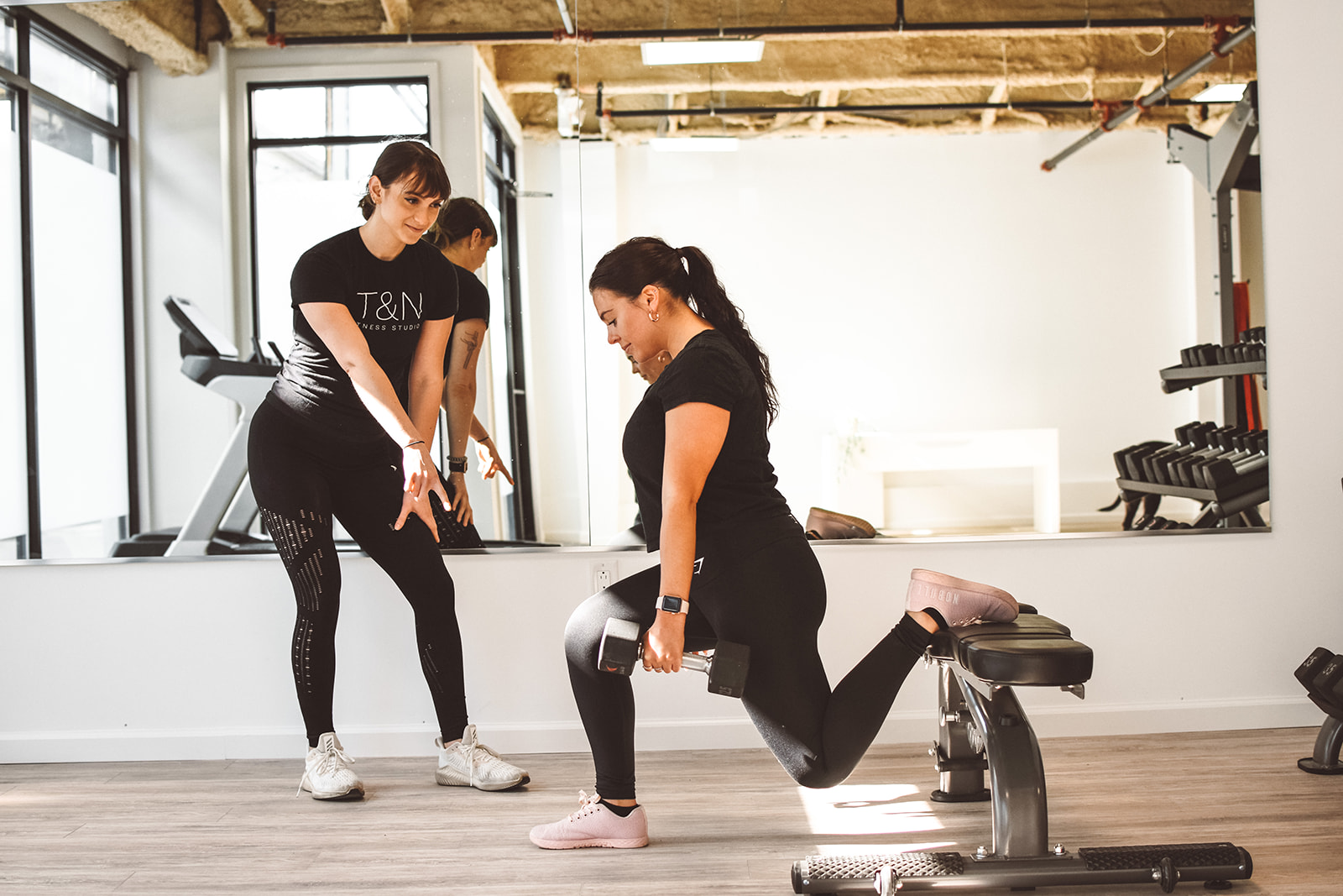Two women engaging in weight training at the gym.