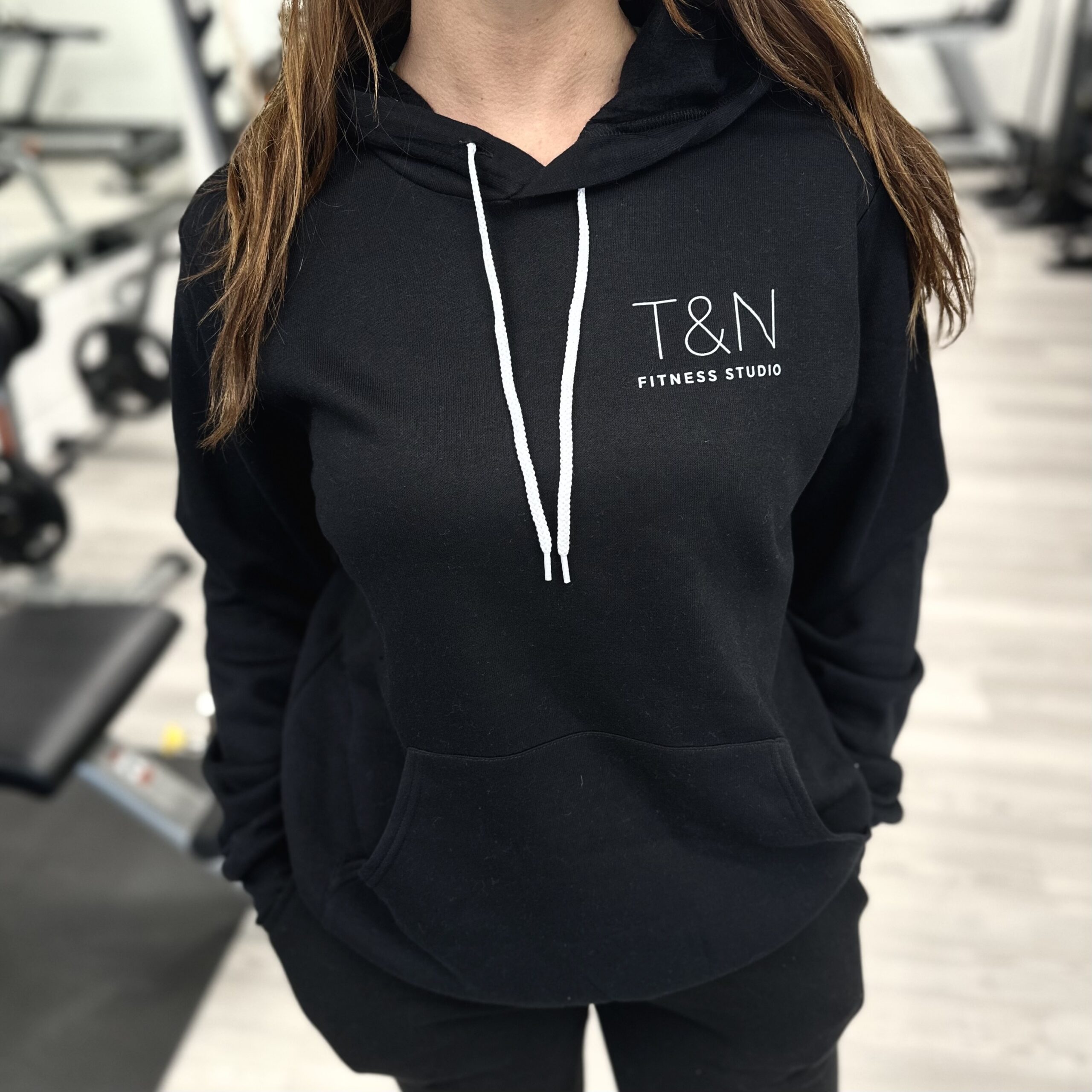A woman wearing a black hoodie in a fitness studio