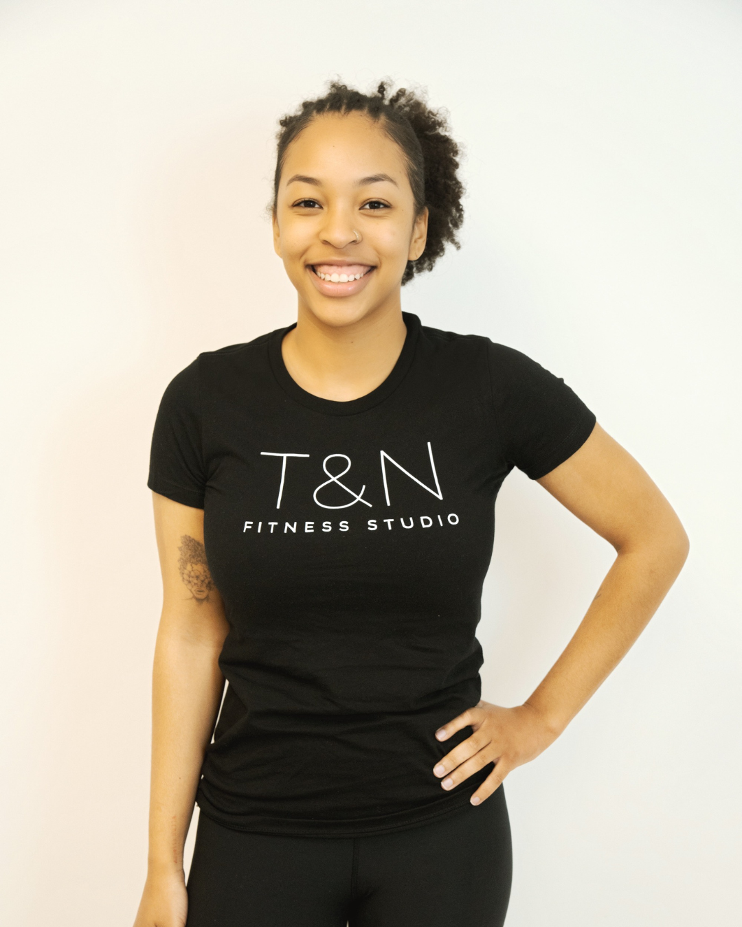A woman wearing a black t-shirt that says TN Fitness Studio is part of the team.