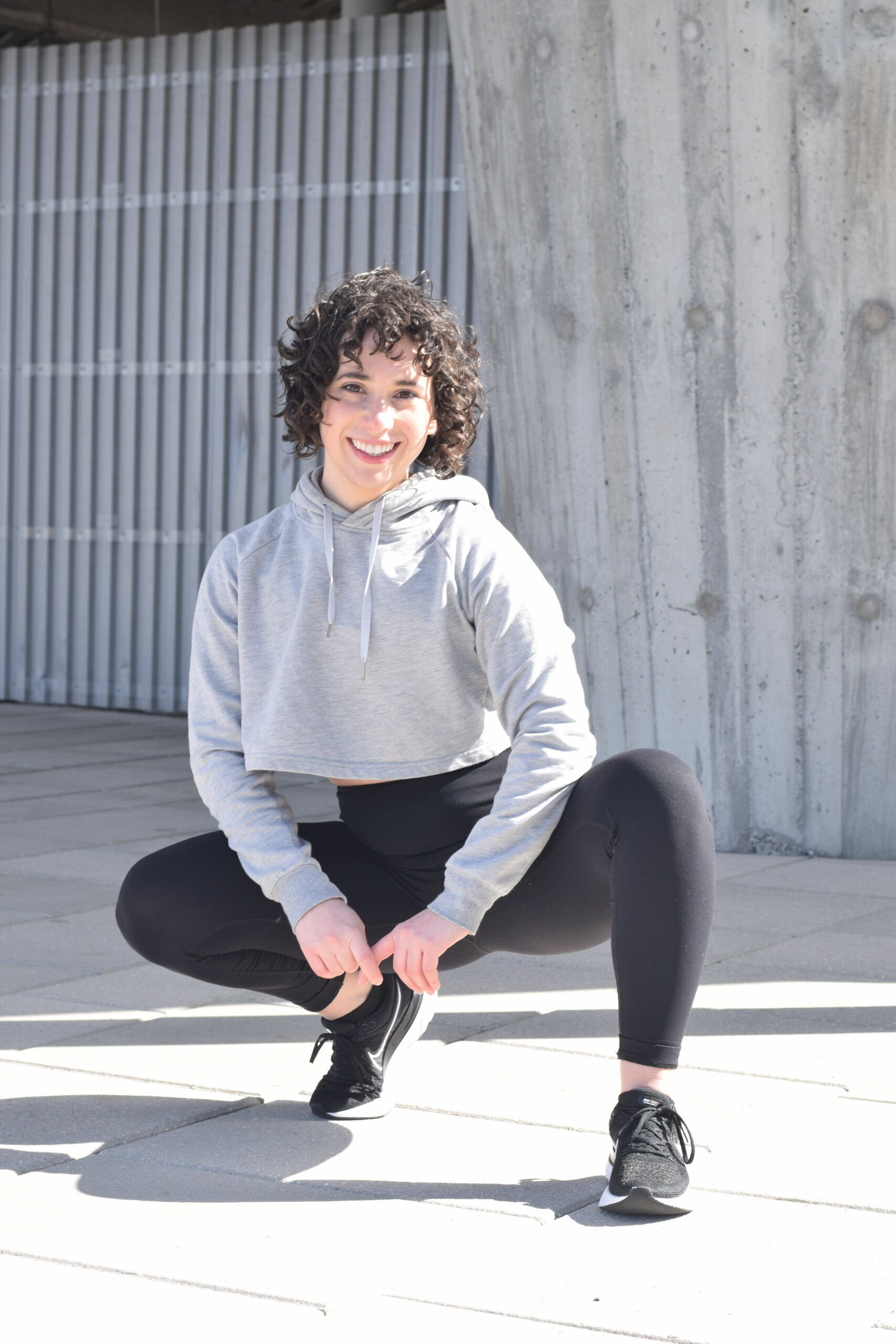 Woman crouching and smiling outdoors in team athletic wear.